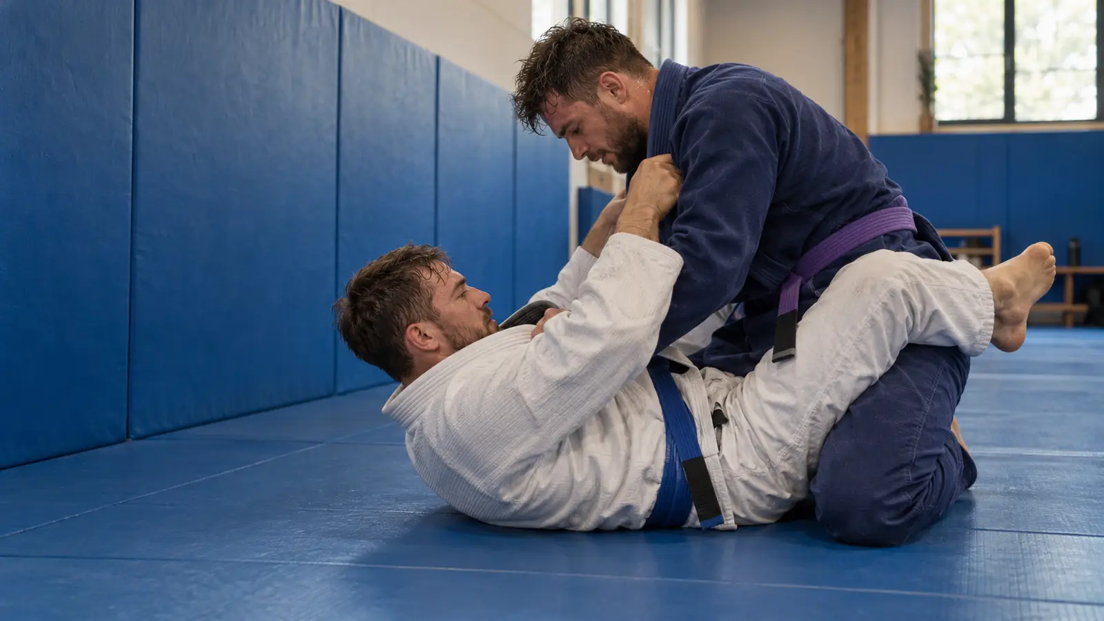 Two BJJ practitioners in gis sparring on the ground